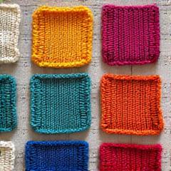 Several brightly colored knitted blanket squares laid out on a surface.