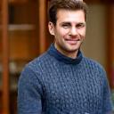 Portrait of Mark, a man holding a beautifully knitted sweater, looking proud
